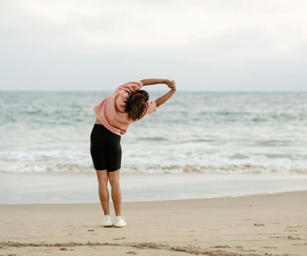 A person stretching outdoors during sunrise, feeling energized.